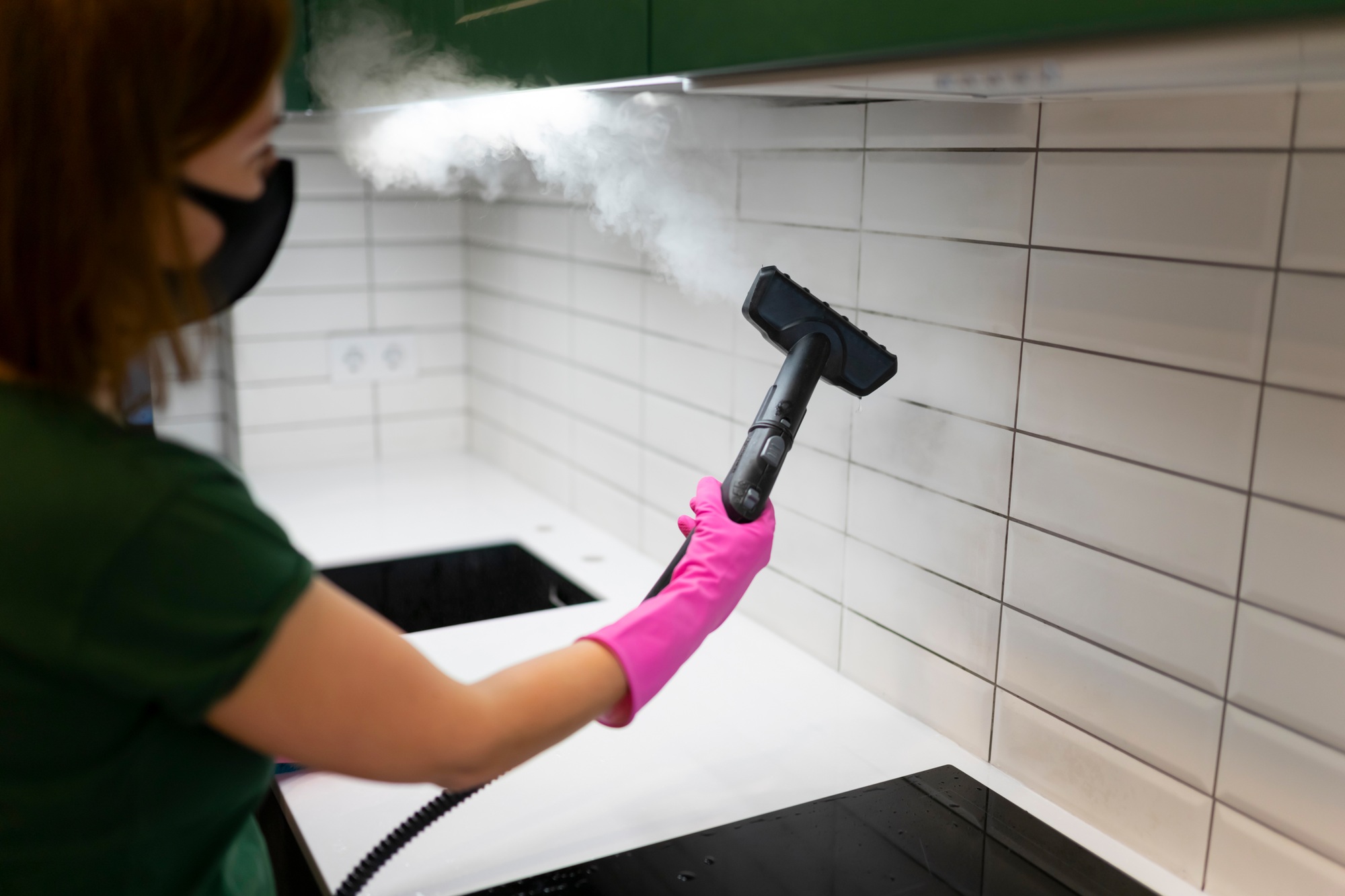 Woman cleaning tiles in the kitchen with steam machine